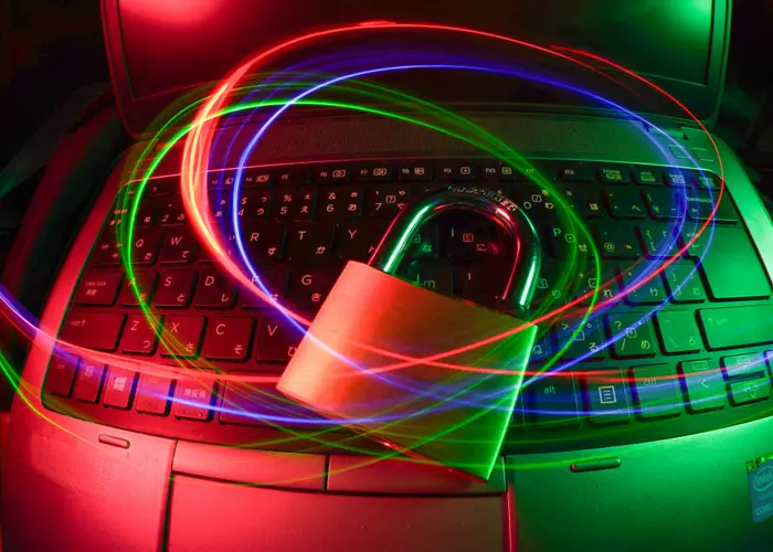 Padlock icon over a laptop keyboard with light trails, representing cyber security